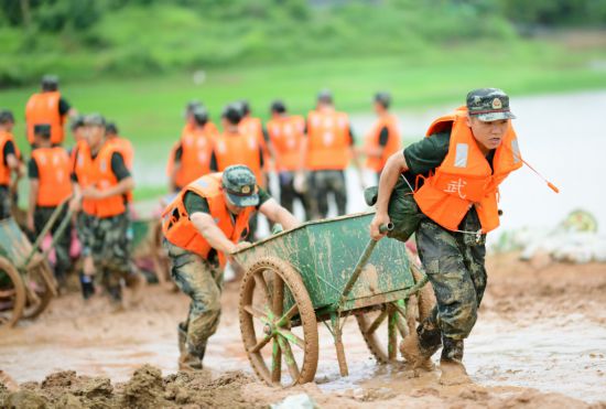 图片说明：7月12日，武警江西总队机动支队官兵在鄱阳县昌江圩利用推车运送沙袋。曹先训摄.png