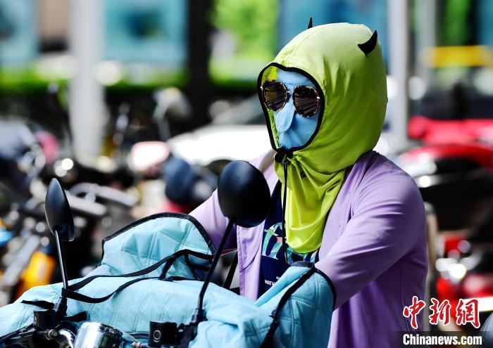 资料图：6月17日，福建福州市民烈日下“全副捂装”出行。　张斌 摄