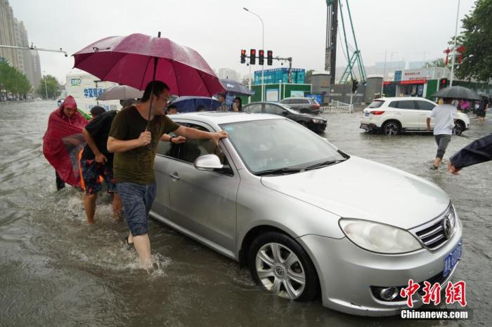 7月20日，河南郑州，一车辆经过积水路段后抛锚，众人帮忙将其推出。近日，郑州连遭暴雨袭击，持续强降雨导致部分街道积水严重。 <a target='_blank' href='http://www.chinanews.com/'><p  align=