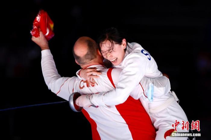 7月24日晚,东京奥运会女子重剑个人赛结束了决赛的较量,中国选手孙一文以11:10战胜罗马尼亚选手波佩斯库,夺得冠军。这是中国体育代表团在本届奥运会的第三枚金牌。图为孙一文夺冠后和团队成员一起庆祝。<a target='_blank' href='http://www.chinanews.com/'><p align=